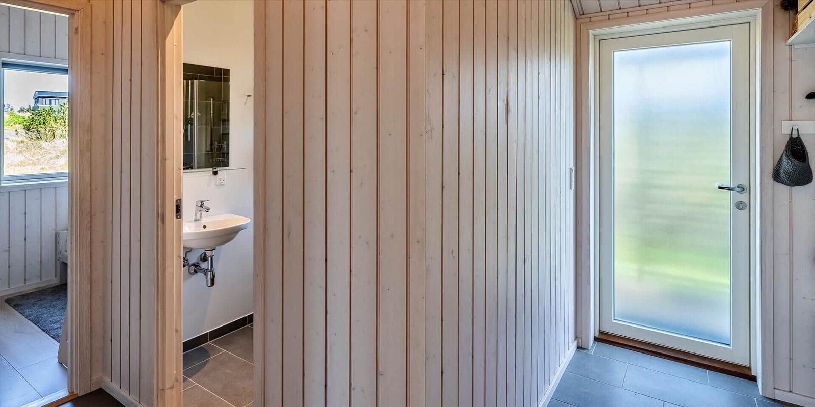 Flur mit Holzwand, Tür und Blick in die Toilette