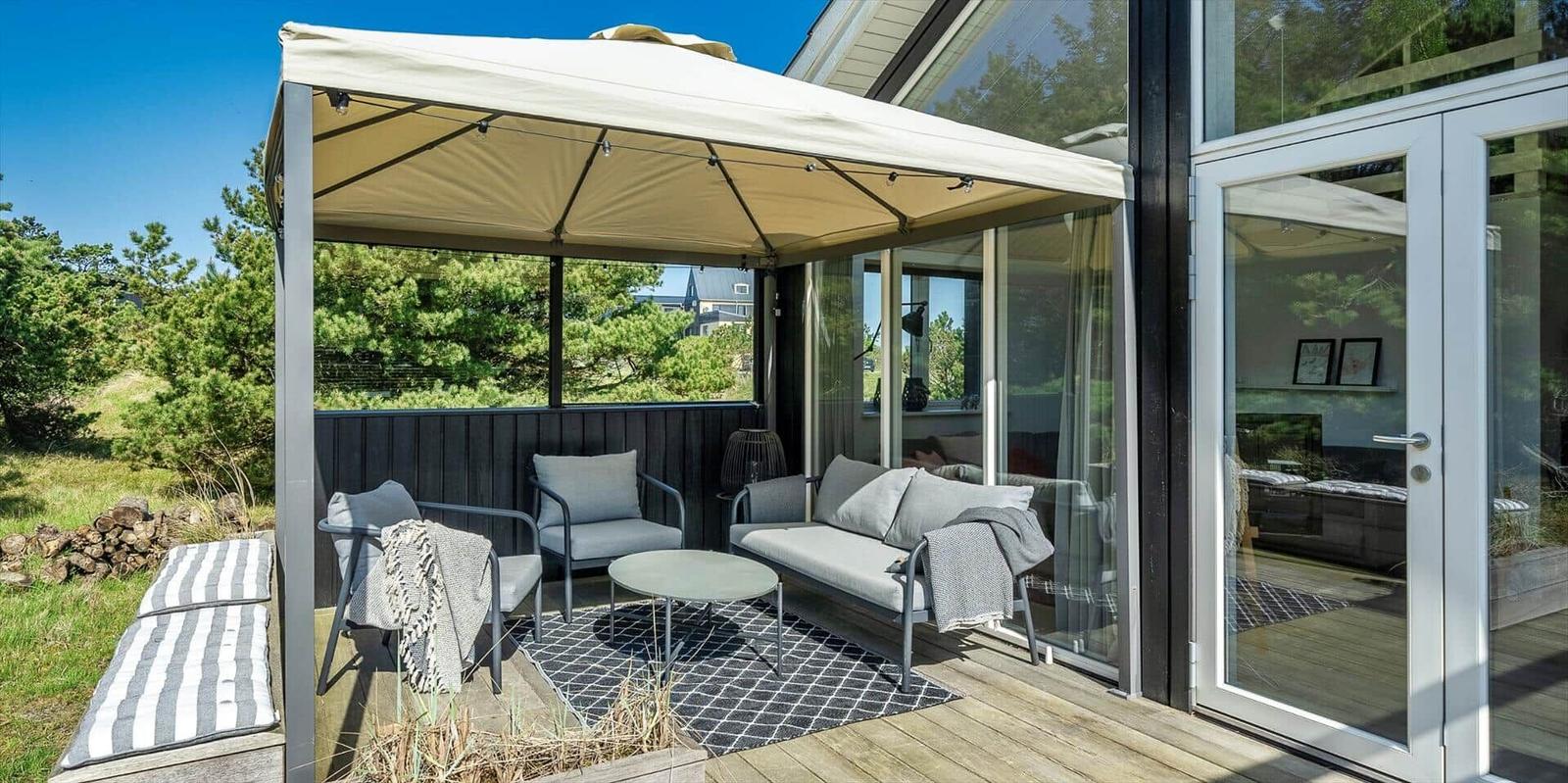 Terrasse mit Pavillon, Sitzmöbel und Blick auf Grünflächen.