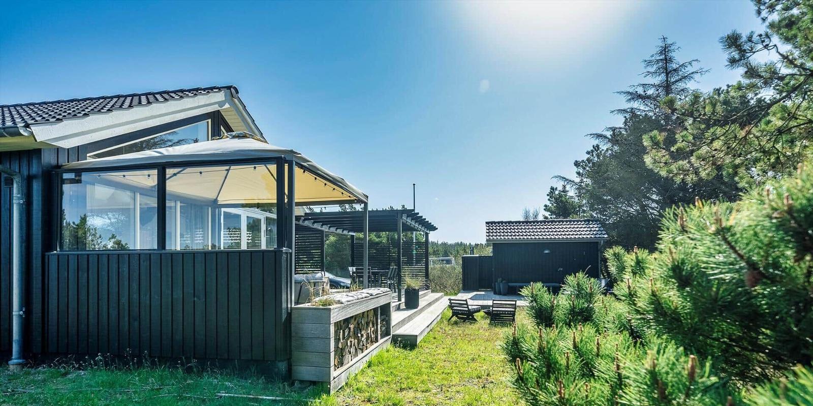 Moderne Villa mit Terrasse, Grillbereich und Garten in grüner Umgebung.