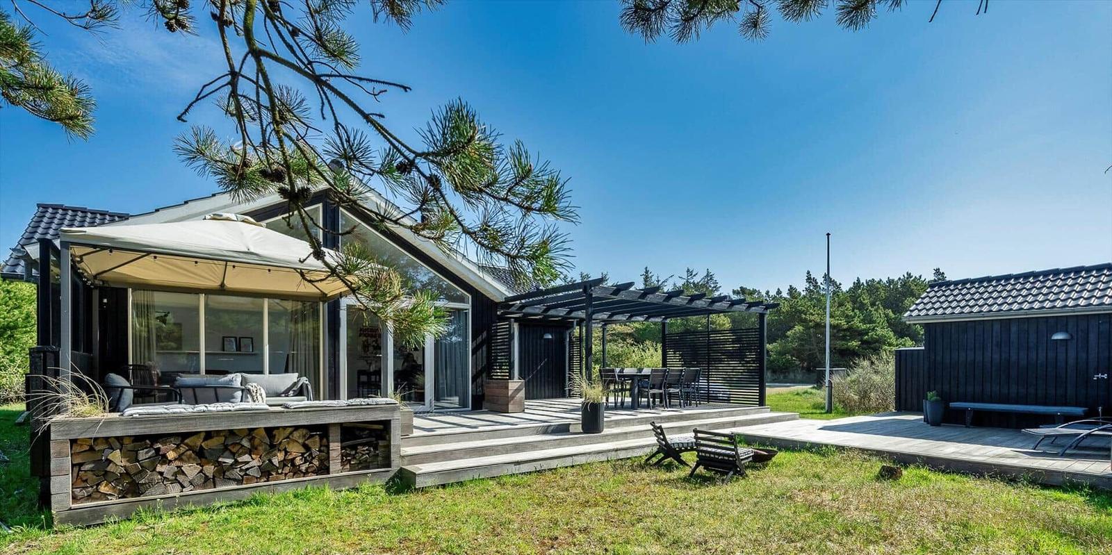 Moderne Villa mit Terrasse, Grillplatz und Garten. Holzstapel und Sitzgelegenheiten.