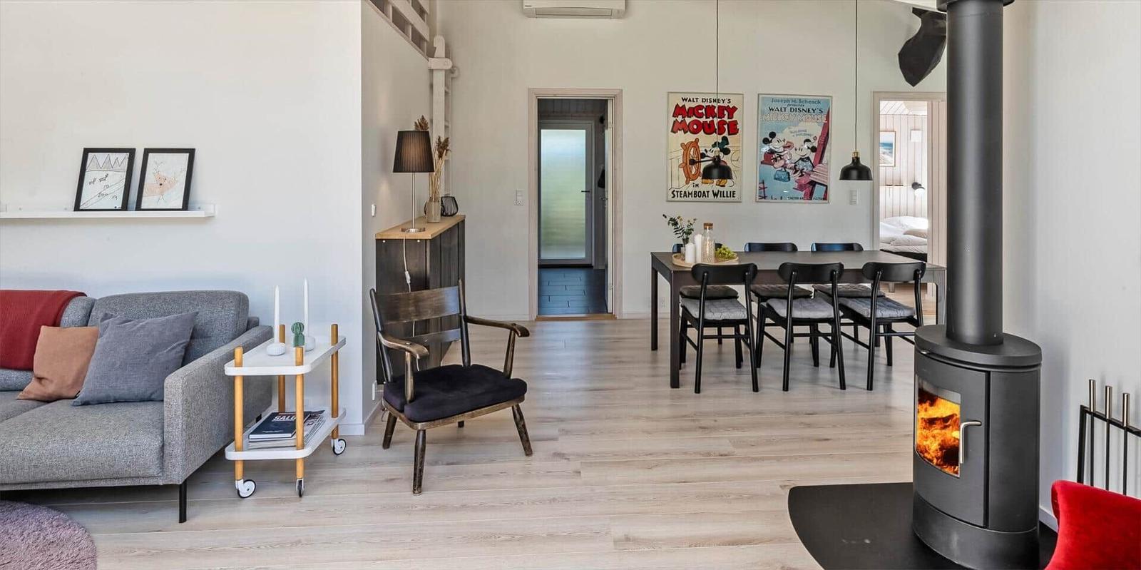 Wohn- und Essbereich mit Kamin, Sofa, Stuhl und Disney-Plakaten an der Wand.