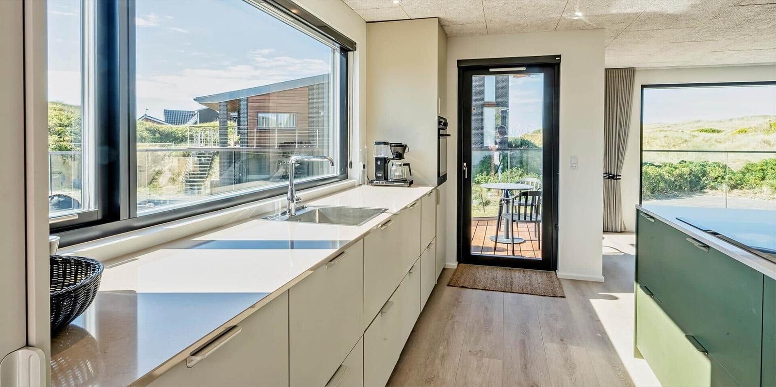 Küche mit großem Fenster und Blick auf Terrasse und Garten