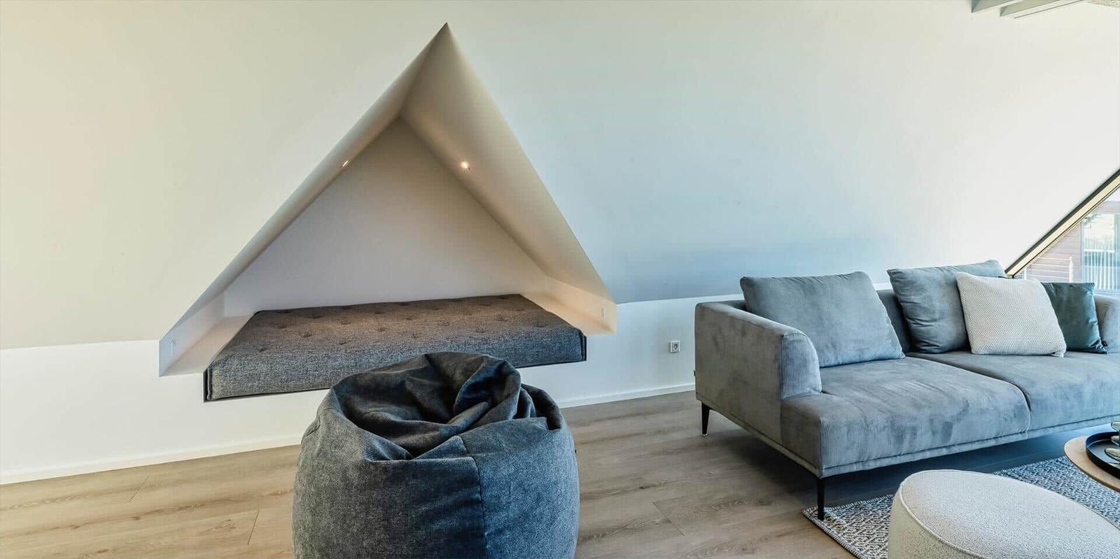 Wohnzimmer mit Sofa, Sitzbank unter Dachschräge und Sitzhocker.