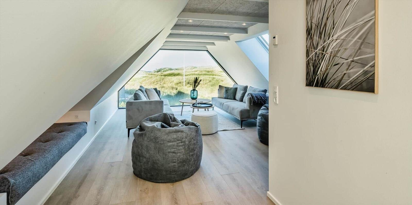 Wohnzimmer mit Sitzgelegenheiten und großem Fenster zur Landschaft