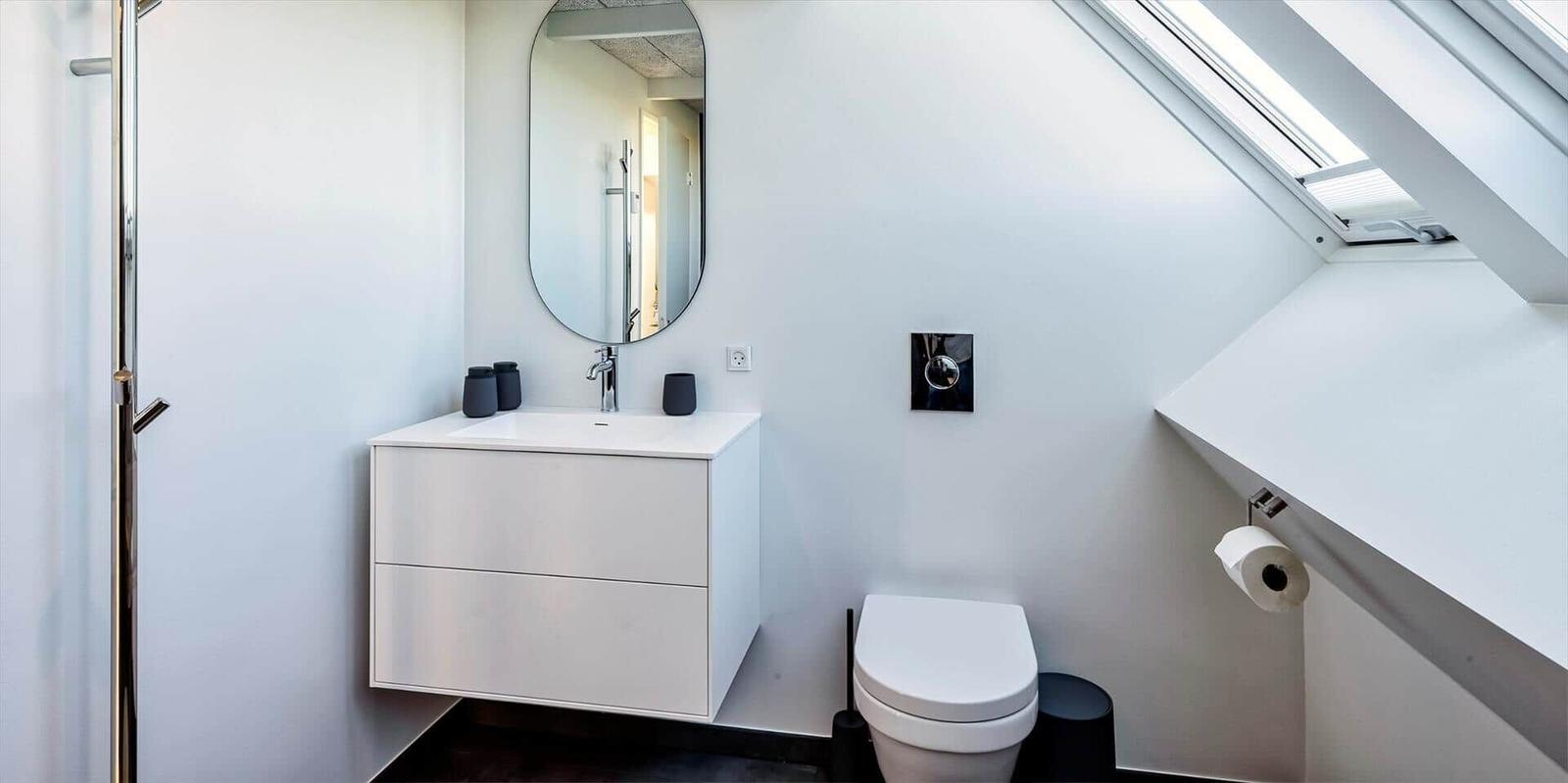 Badezimmer mit Waschbecken, Toilette und Dachschräge