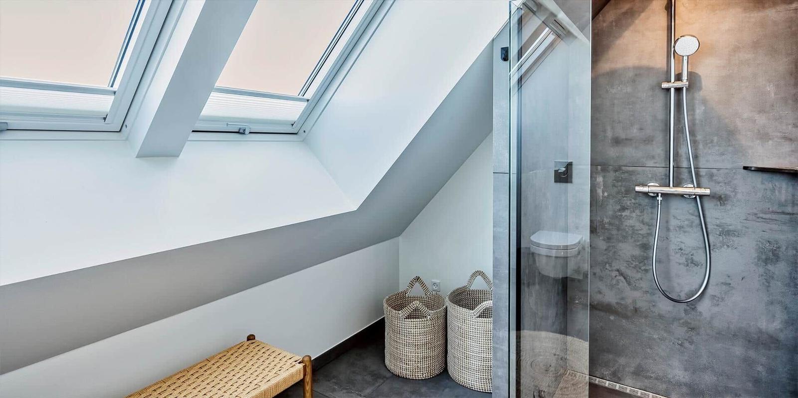 Dusche mit Glaswand, Dachfenster und zwei Körben.