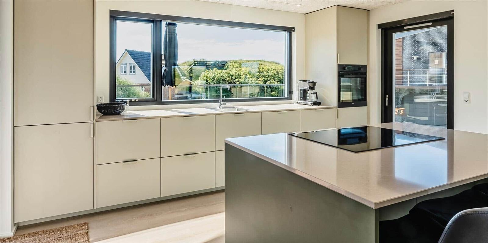 Moderne Küche mit Kücheninsel und großem Fenster zur Terrasse