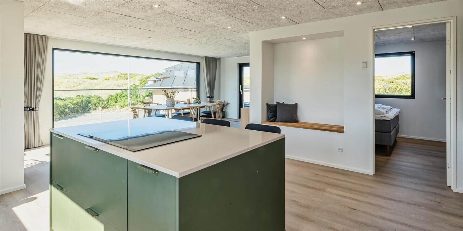 Moderne Küche mit Kücheninsel, Essbereich und Blick auf die Landschaft.