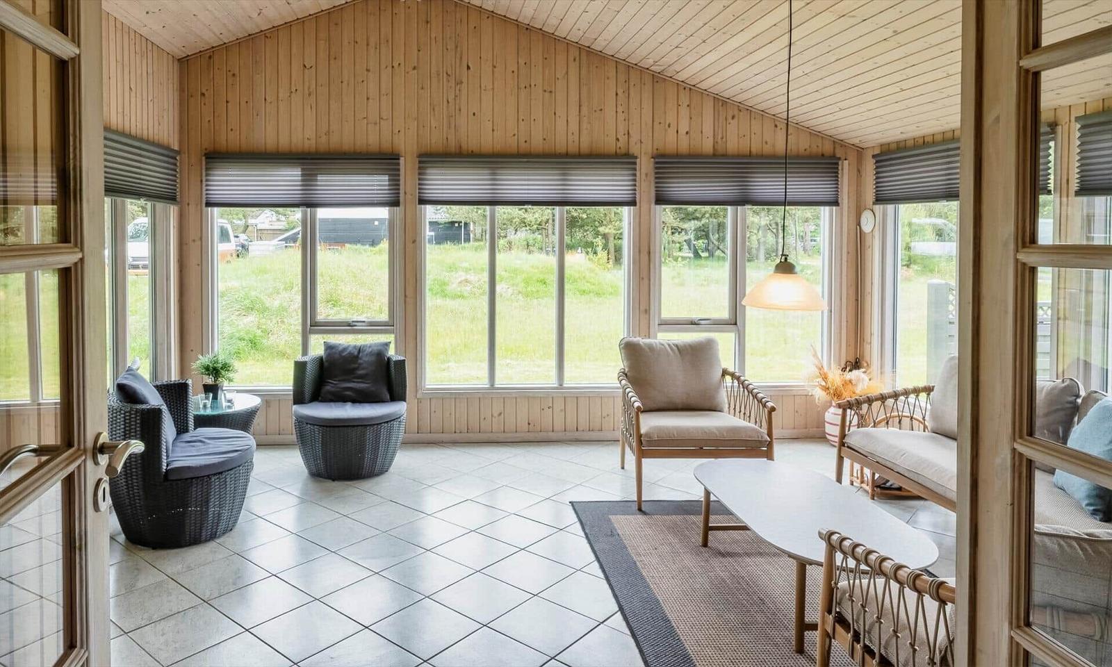 Großes Wohnzimmer mit Holzwänden und Fenstern zum Garten.