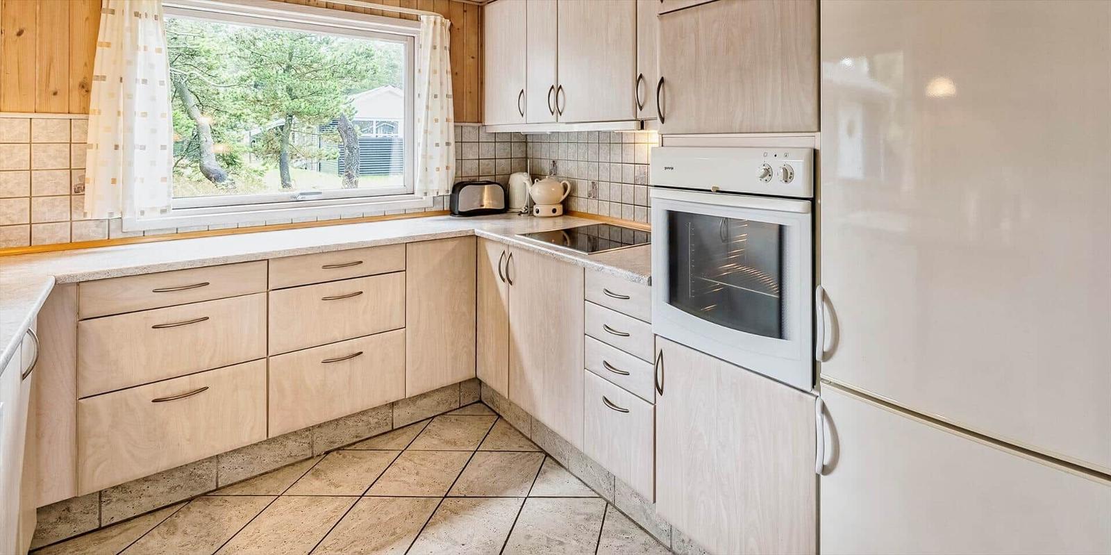 Küche mit Holzschränken, Backofen und Blick auf Außenbereich
