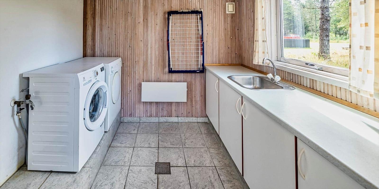Wohnung mit Waschmaschine, Trockner und Waschbecken an Fenster.