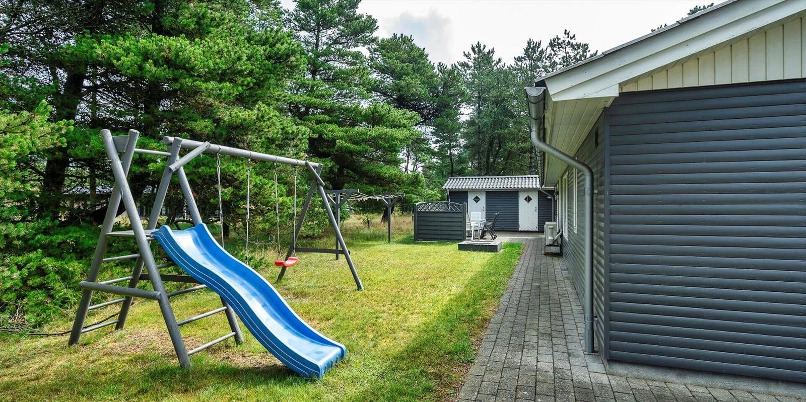 Hinter dem Haus befindet sich ein Spielplatz mit Rutsche und Schaukel.