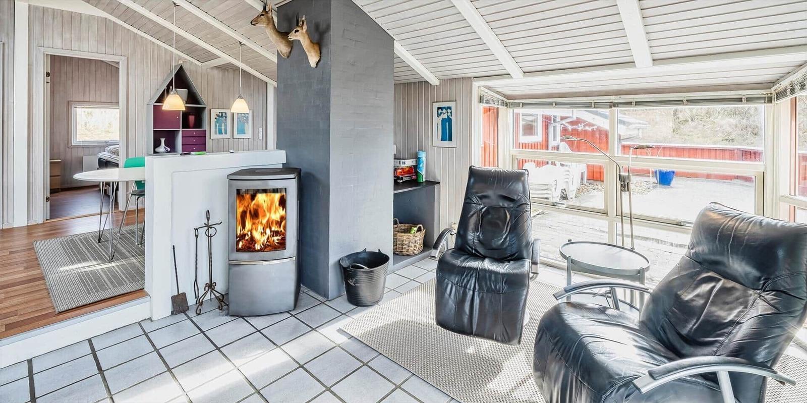 Wohnbereich mit Kamin, zwei Ledersessel und großem Fensterblick.