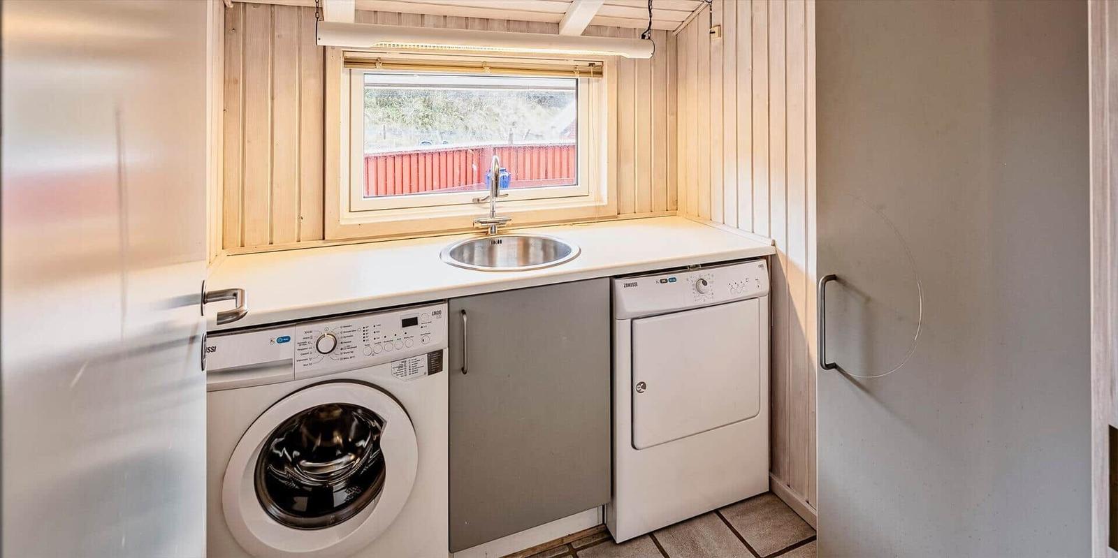Wohnung mit Waschmaschine, Trockner und Waschbecken unter Fenster.
