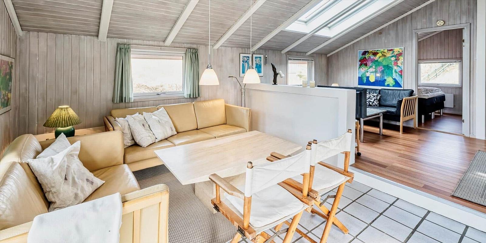 Wohnraum mit Sofa, Tisch und Stühlen. Durchgang zu Schlafzimmer mit Bett.