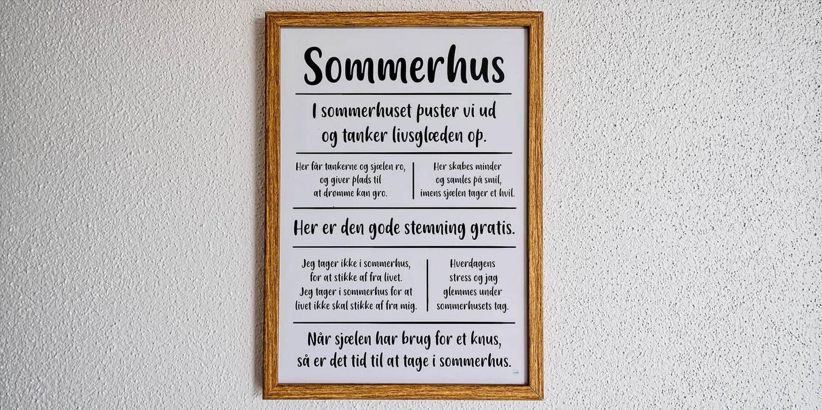 Ein gerahmtes Schild mit Text über das Sommerhaus an der Wand.