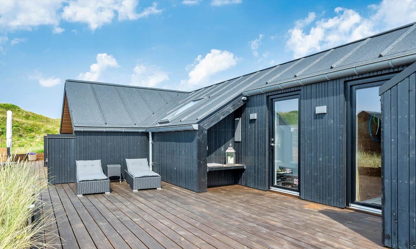 Terrasse mit Loungemöbeln und Blick auf grüne Hügel.