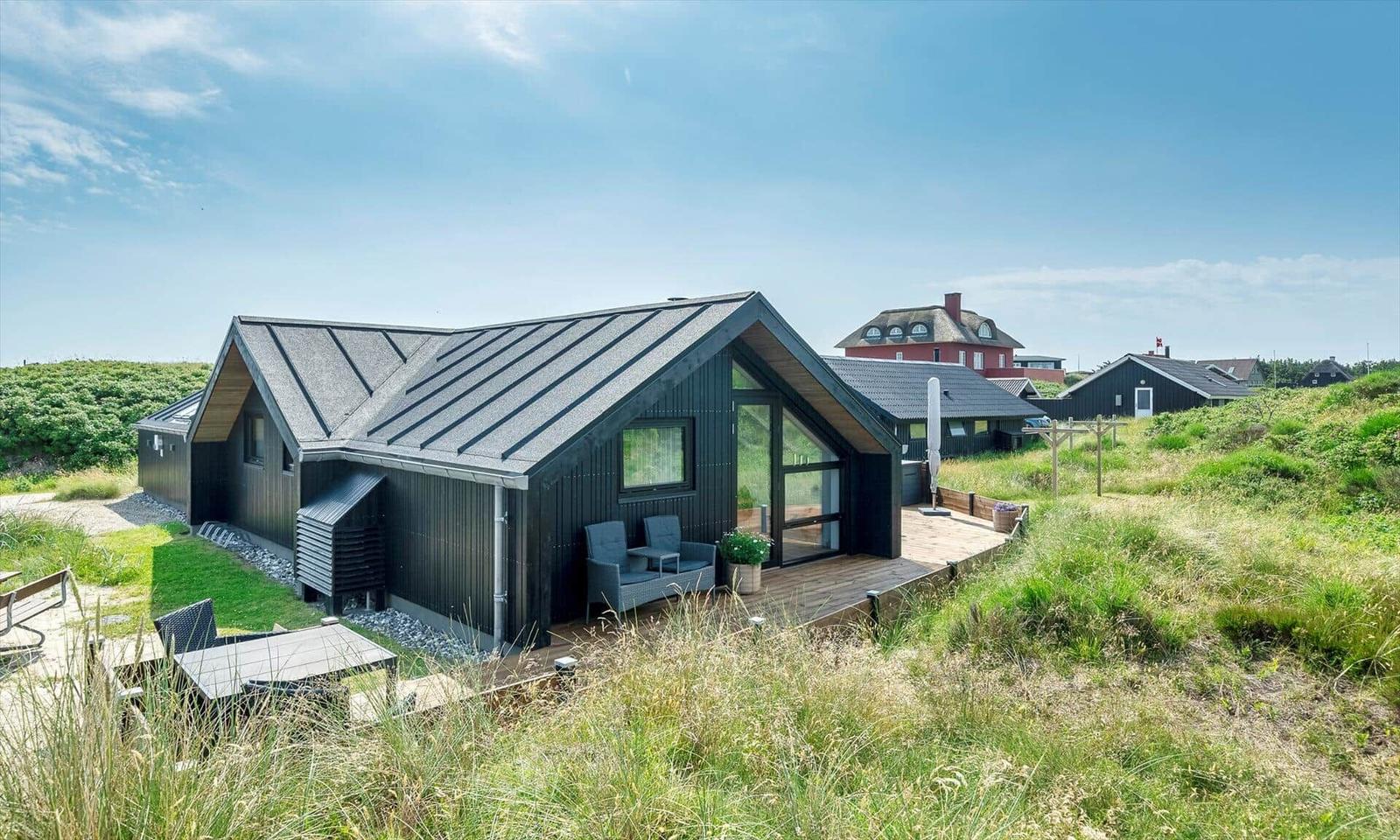 Moderne Holzhütte mit Terrasse und Garten. Blick auf umliegende Häuser.