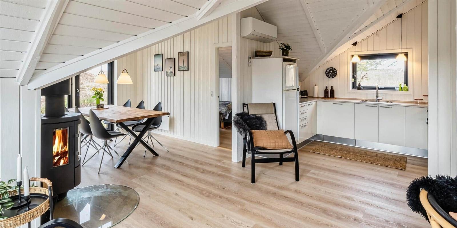 Wohnküche mit Esstisch, Kamin und Küchenzeile unter Dachschräge.