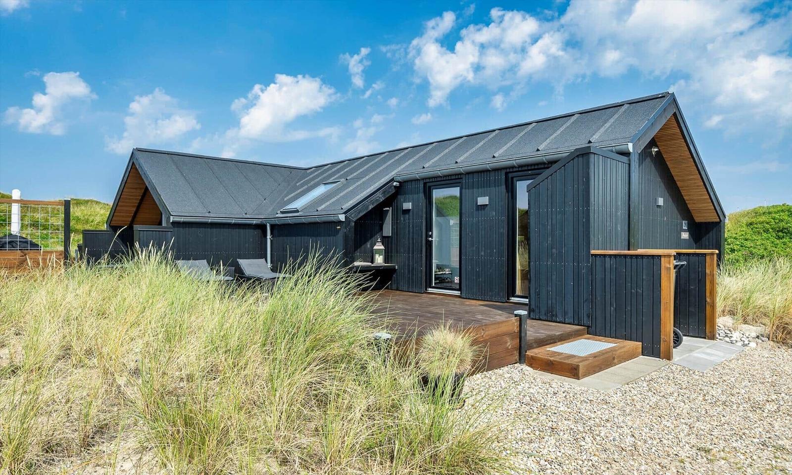 Moderne Strandhütte mit Terrasse und Sitzgelegenheiten.