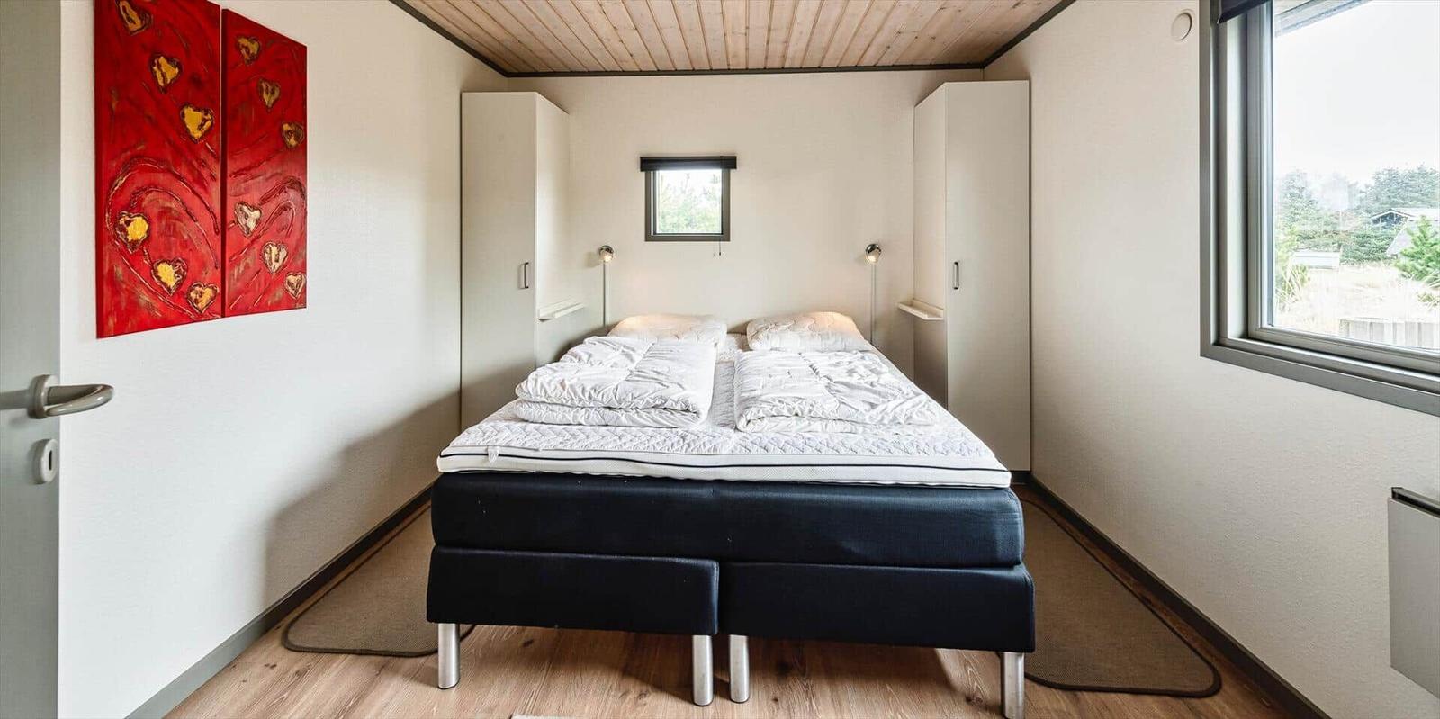 Schlafzimmer mit Bett, Kleiderschränken und Fenster. Wandbild mit Herzen.