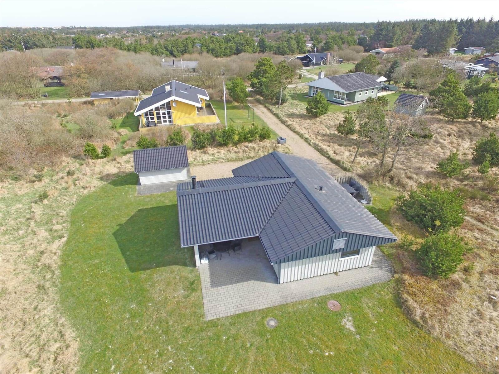 Haus mit dunklem Dach und Terrasse auf grünem Grundstück