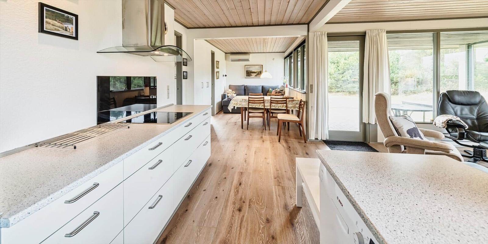 Moderne Küche mit Essbereich und Wohnzimmer. Holzboden und große Fenster.