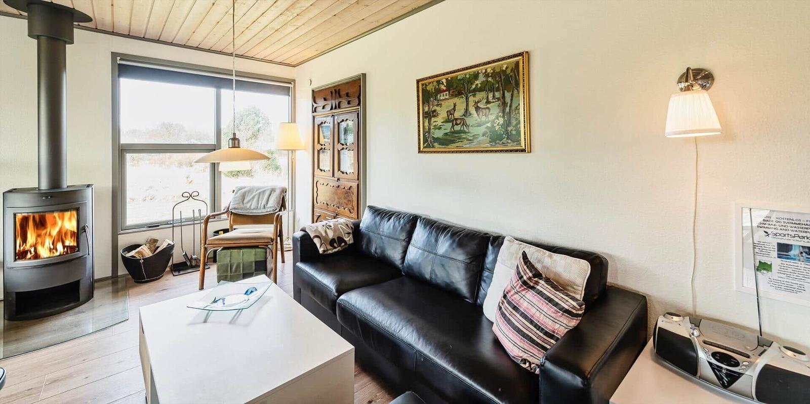 Wohnzimmer mit Sofa, Kamin und Fensterblick.