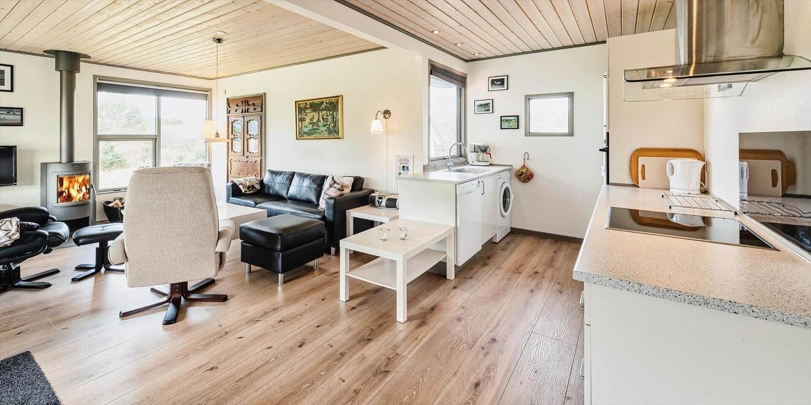 Wohn- und Küchenbereich mit Holzboden, Kamin und moderner Küche.
