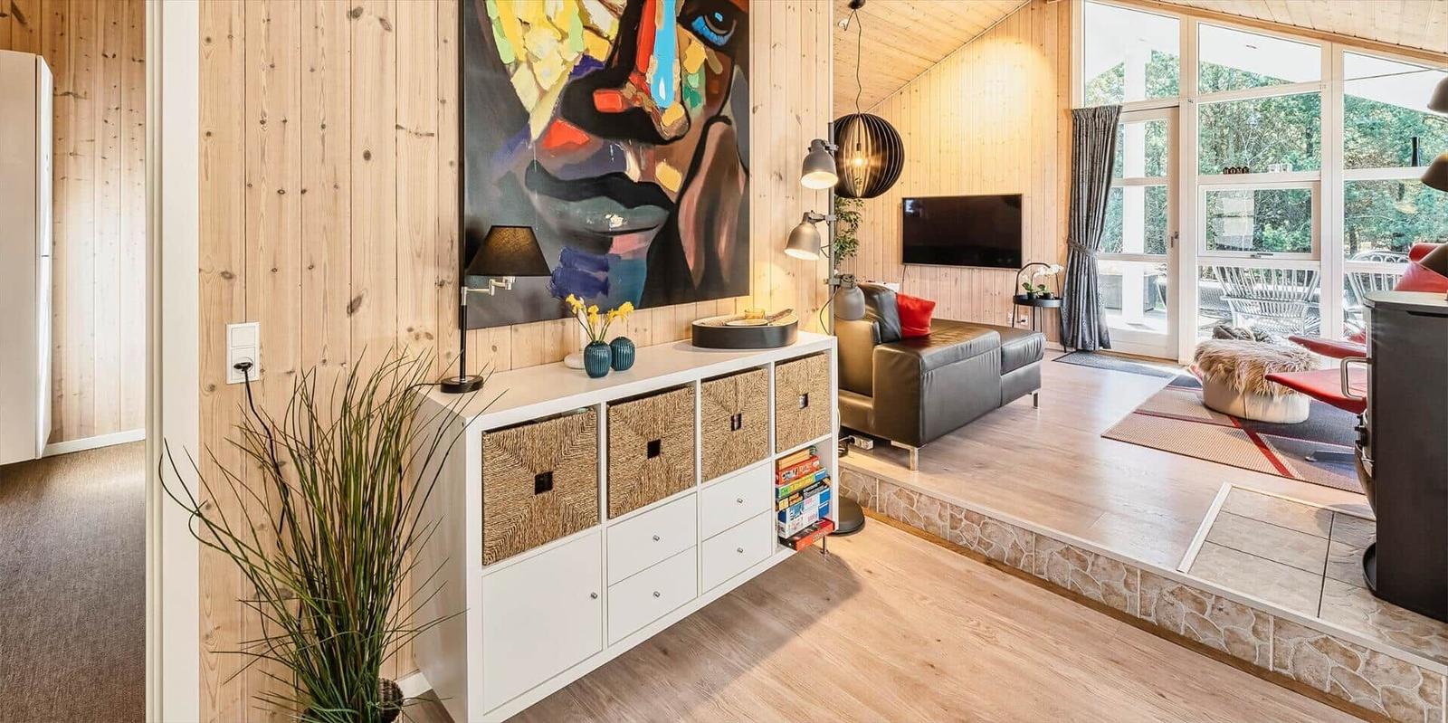 Wohnzimmer mit Holzwand, Sofa, Fernseher und großem Fenster zur Terrasse.