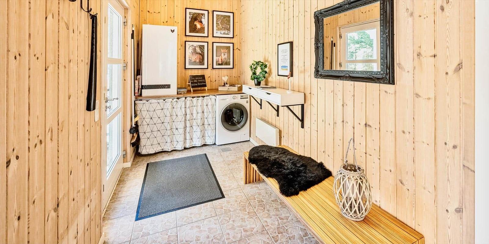 Wohnung mit Holzwand, Waschmaschine und Bänkchen mit Felldecke.