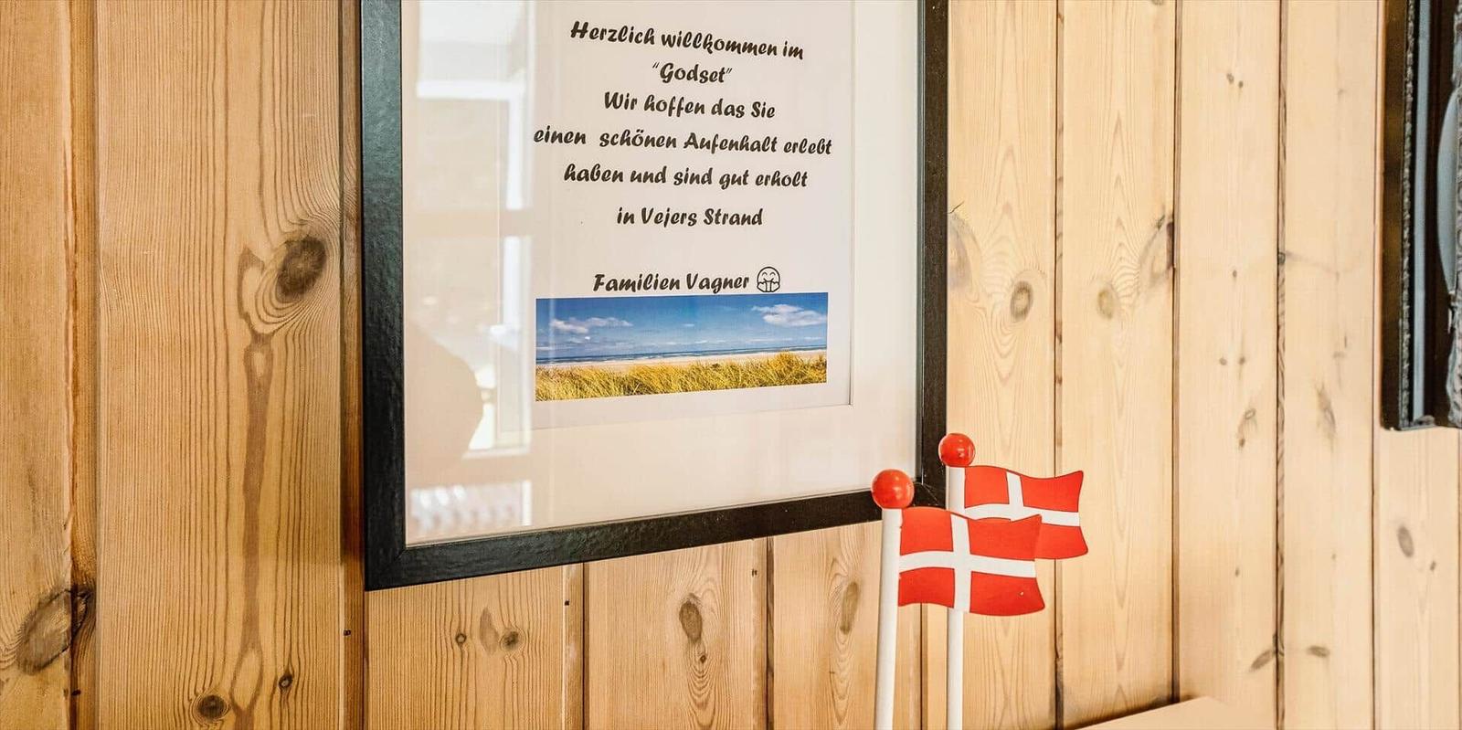 Willkommensschild an Holzwand mit dänischen Flaggen