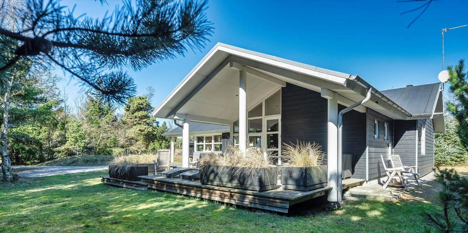 Moderne Holzhütte mit Terrasse und Garten im Wald.