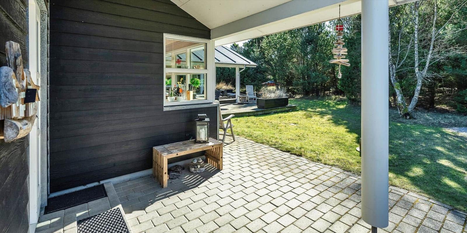 Terrasse mit Holzbank, Fenster und Blick auf den Garten.