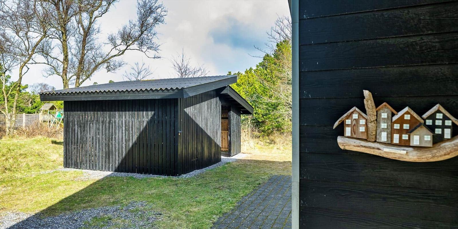 Schwarzes Holzhaus mit Dach und Tür. Holzfigur mit Häusern auf Wand.