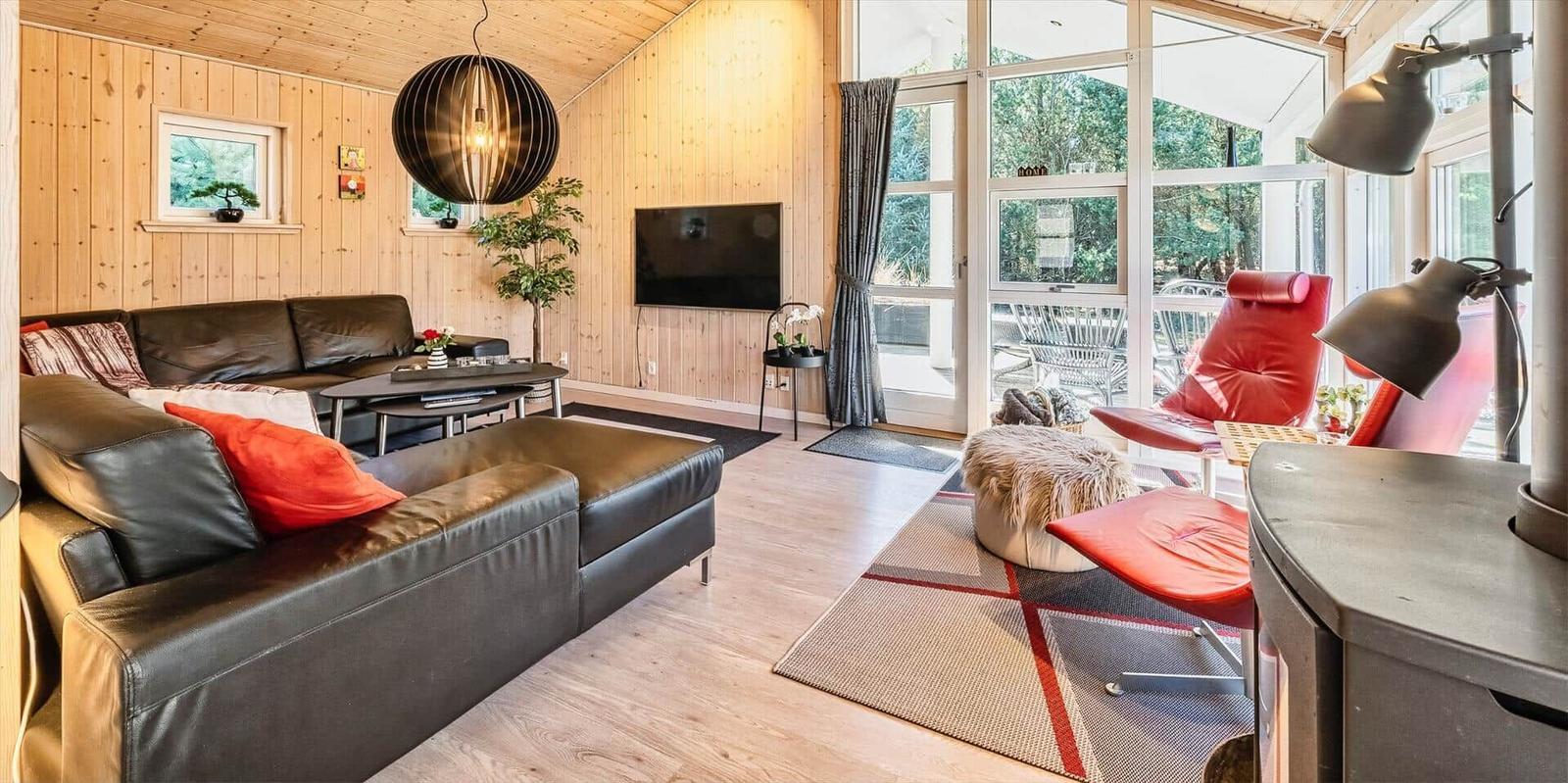 Wohnzimmer mit Ledersofa, rotem Sessel und Holzwand