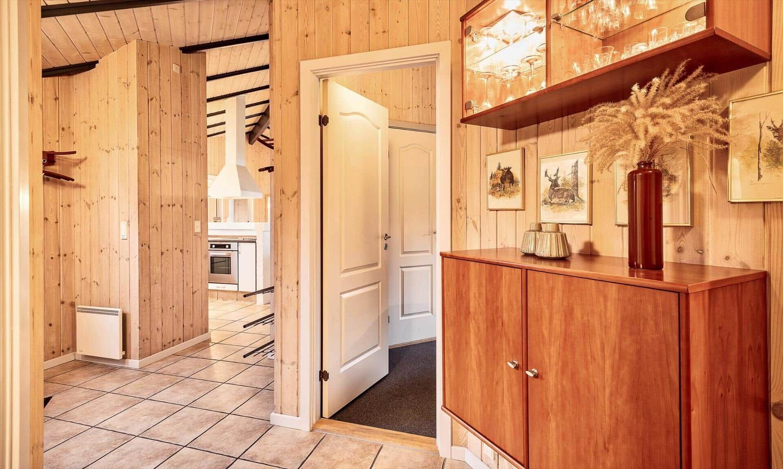 Eingangsbereich mit Holzwand, Schrank und Blick in Küche.