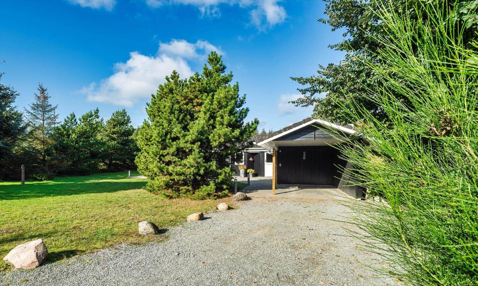 Haus mit Garage, Grasfläche und Bäumen unter blauem Himmel.