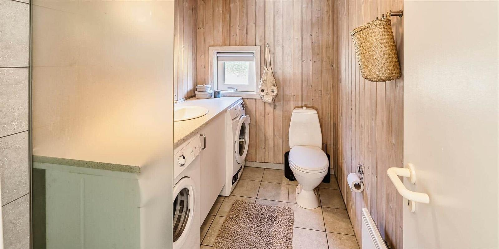 Badezimmer mit Waschmaschine, Toilette und Holzwand