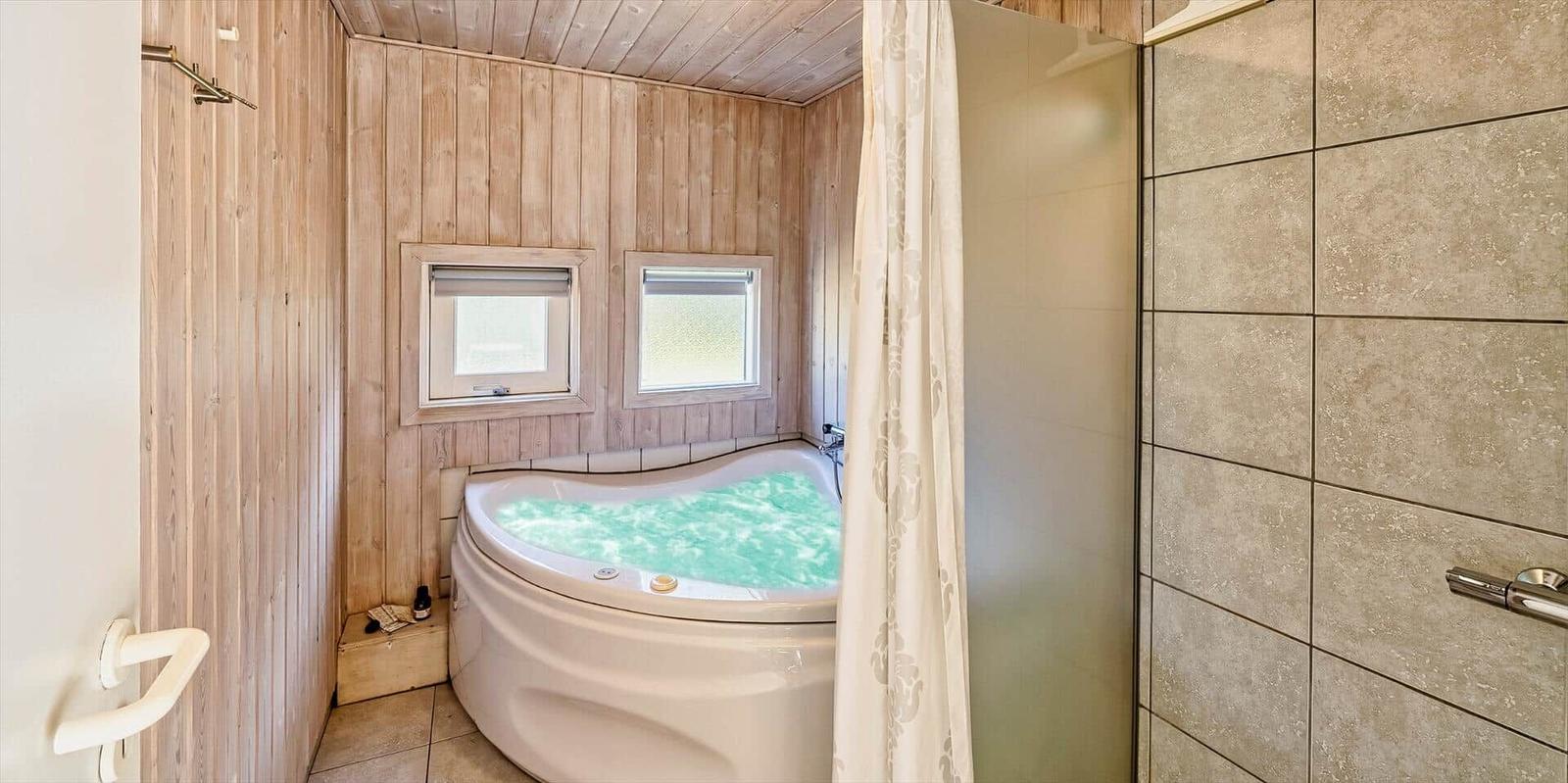 Bad mit Whirlpool, Holzwand und zwei Fenstern.