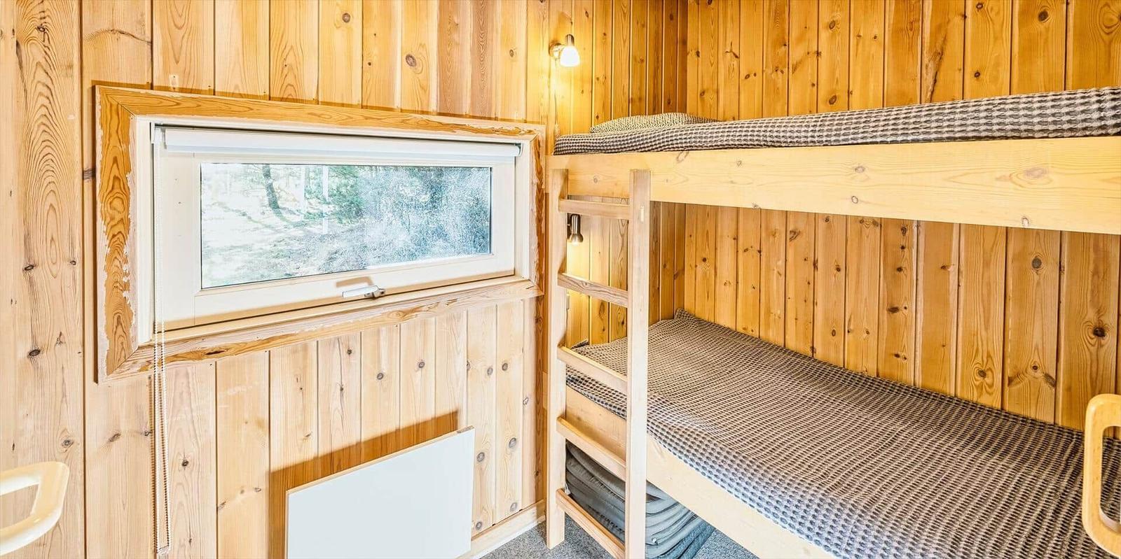 Zimmer mit Doppelstockbett und Fenster zur Waldansicht