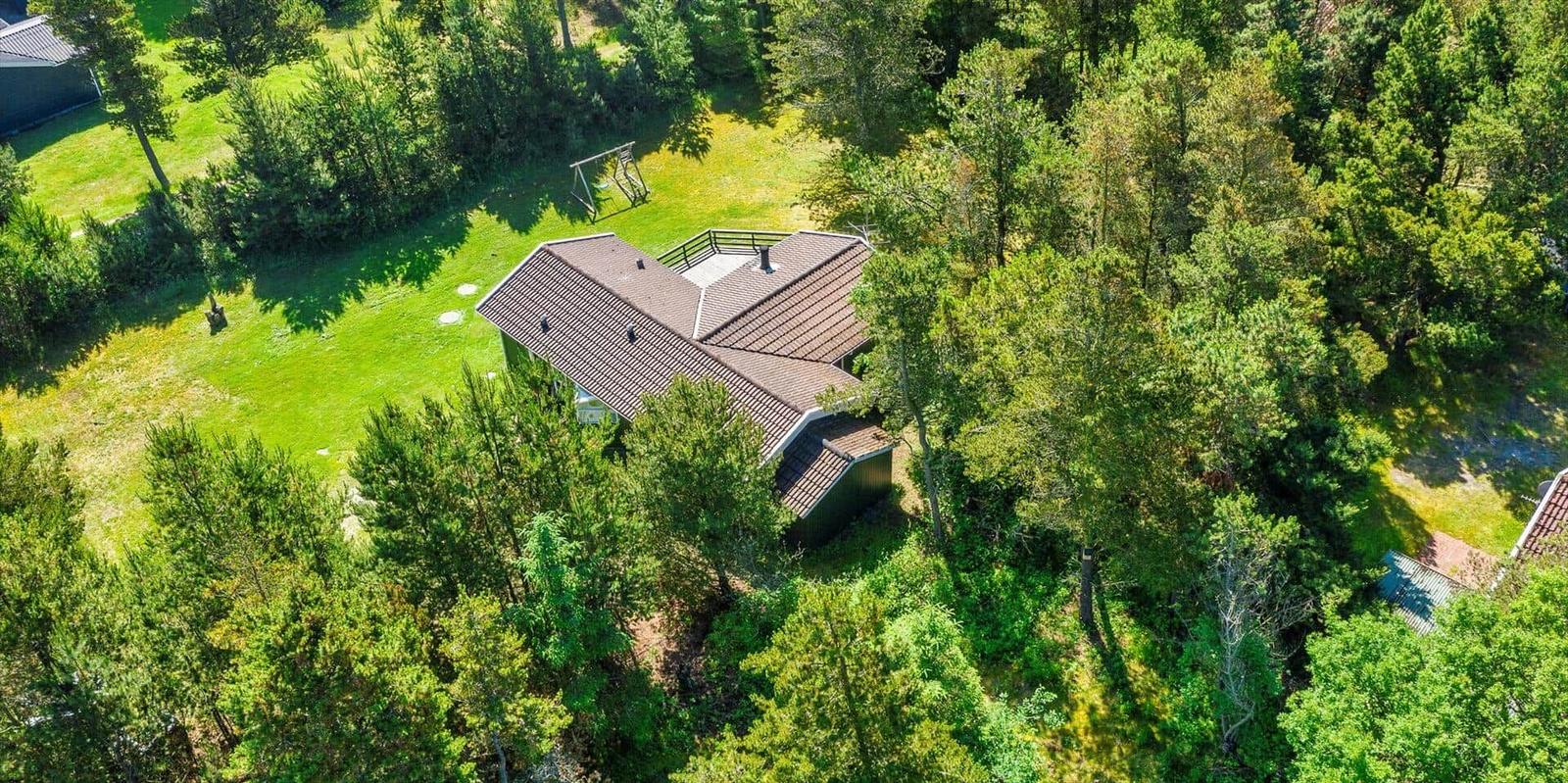 Haus mit Terrasse im Wald, grüner Rasen und Spielplatz