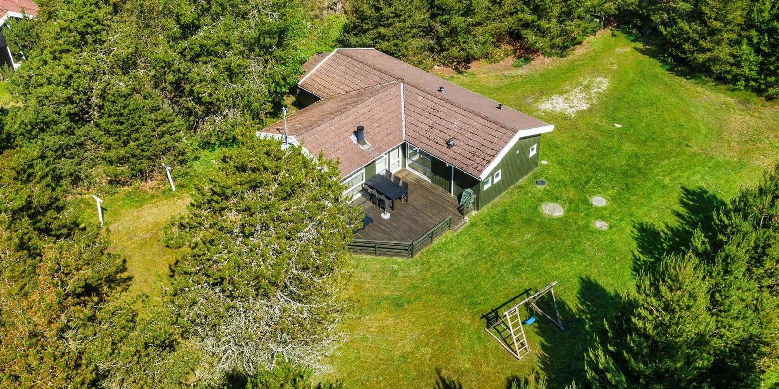 Grünes Haus mit Terrasse und Spielplatz im Wald.