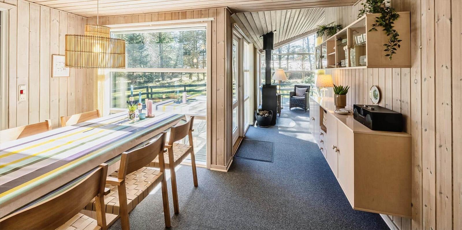 Essbereich mit Tisch und Stühlen, Blick auf Terrasse und Wohnzimmer mit Kamin.
