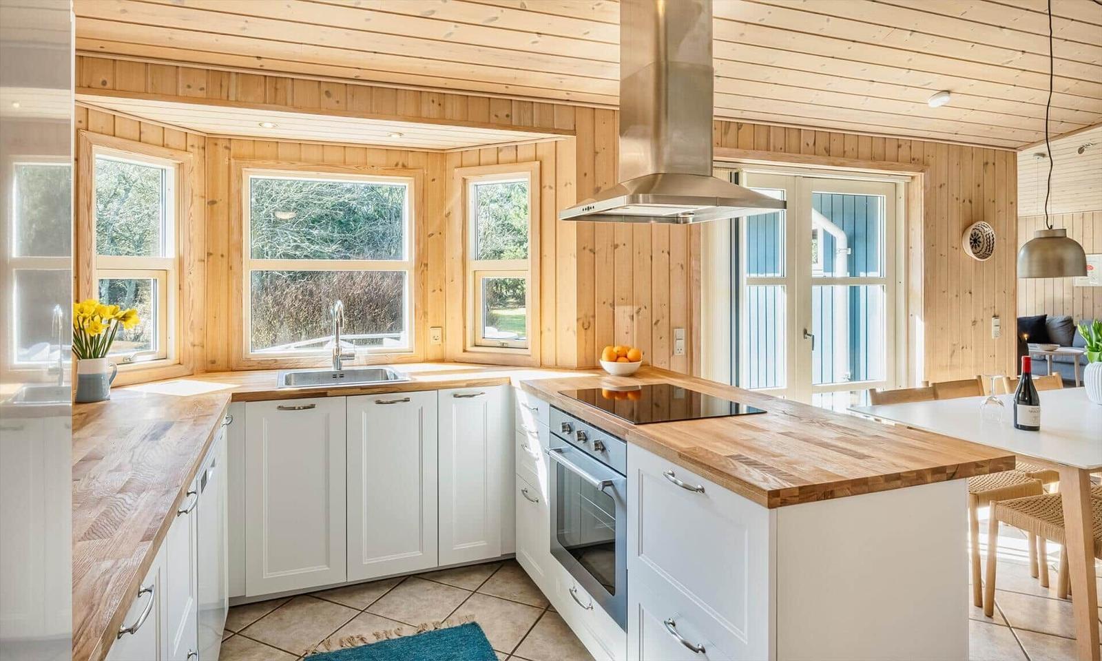 Küche mit Holzwänden, weißen Schränken und Holzoberflächen.