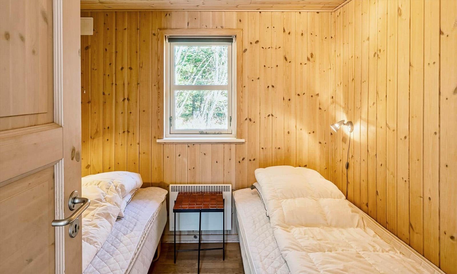 Zwei Betten in einem Holzraum mit Fenster und Tisch.