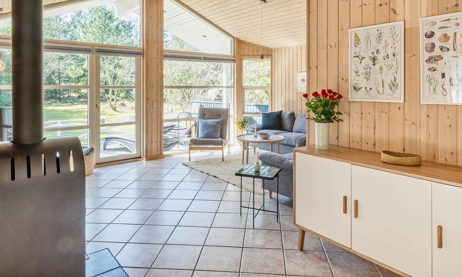 Wohnbereich mit Holzwänden, Sitzgelegenheiten und Blick auf Garten.