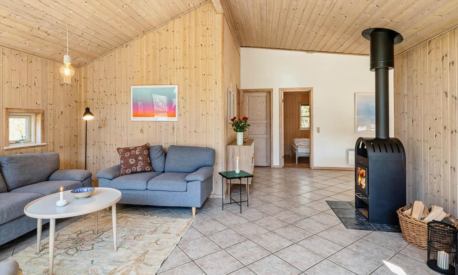 Wohnzimmer mit Holzwand, Sofa, Kamin und Blick in Schlafzimmer.