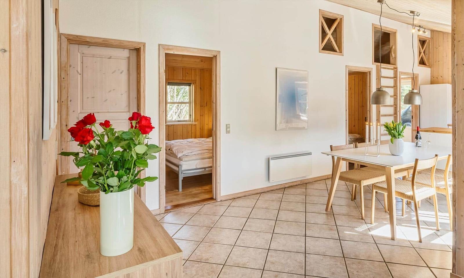 Wohnraum mit Essbereich, Schlafzimmer und Blumen auf Tisch.