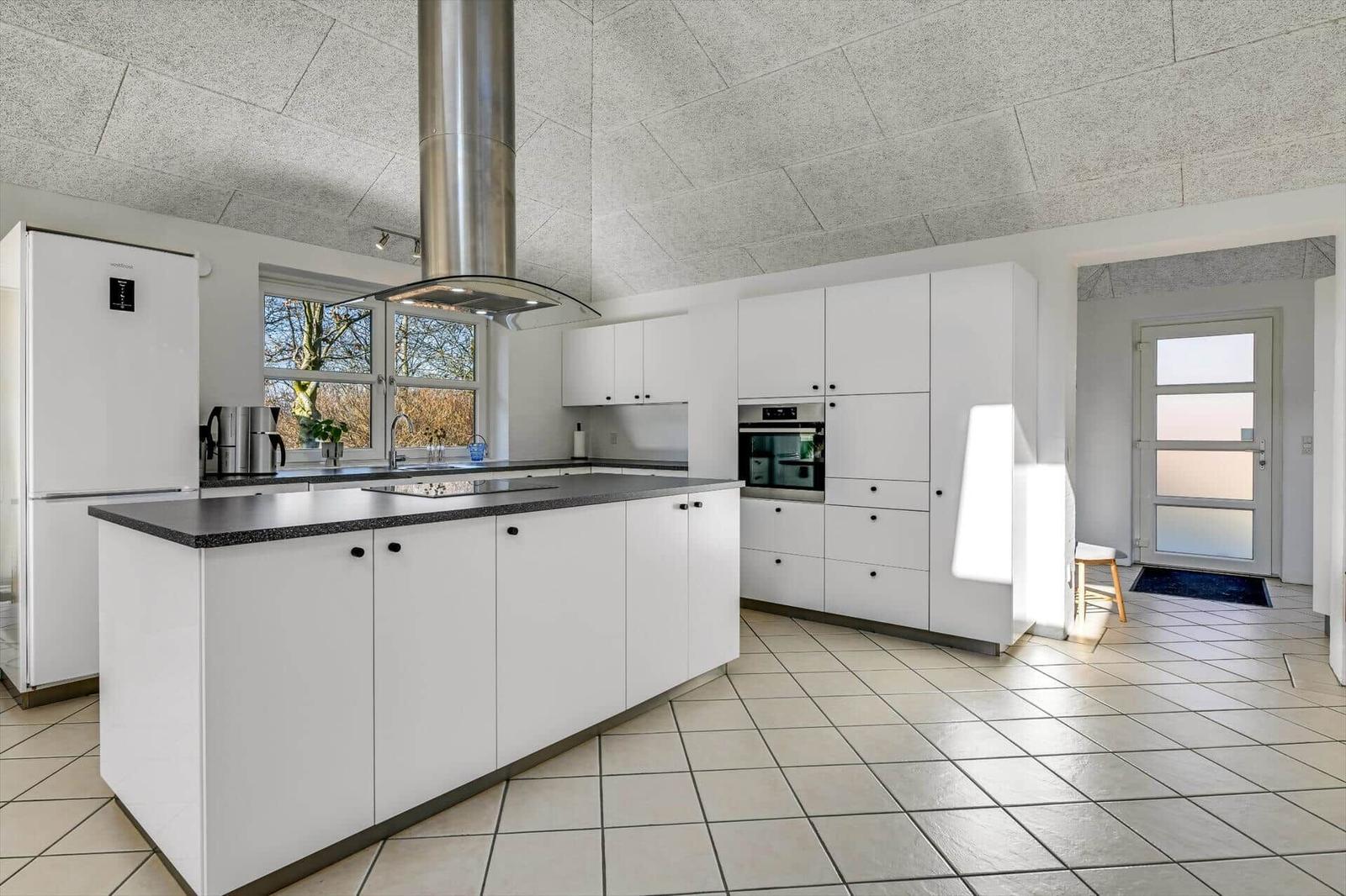 Moderne Küche mit weißer Einbauküche, Edelstahlherd und Fensterblick.